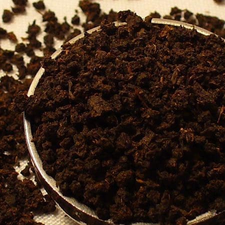Close-up of dark brown soil or compost in a container.