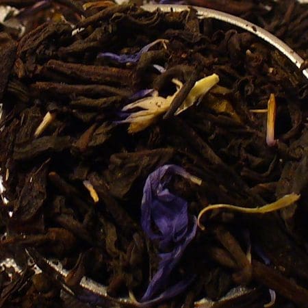 Close-up of dried purple flowers and brown stems on a dark surface.
