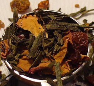 Close-up of dried herbal tea leaves and petals in a metal container.