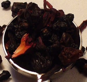 A bowl of dried chili peppers on a white surface.