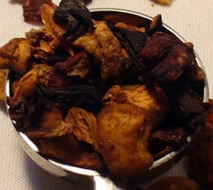 Dried fruit and spices in metal scoop.