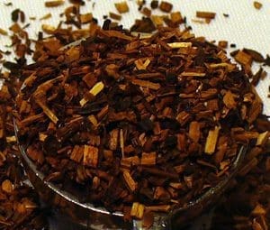 Close-up of dried herbal tea leaves in a glass container.