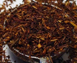 Close-up of loose rooibos tea leaves in a container.