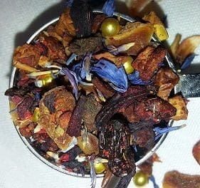 A bowl filled with dried herbs, flowers, and spices for tea.