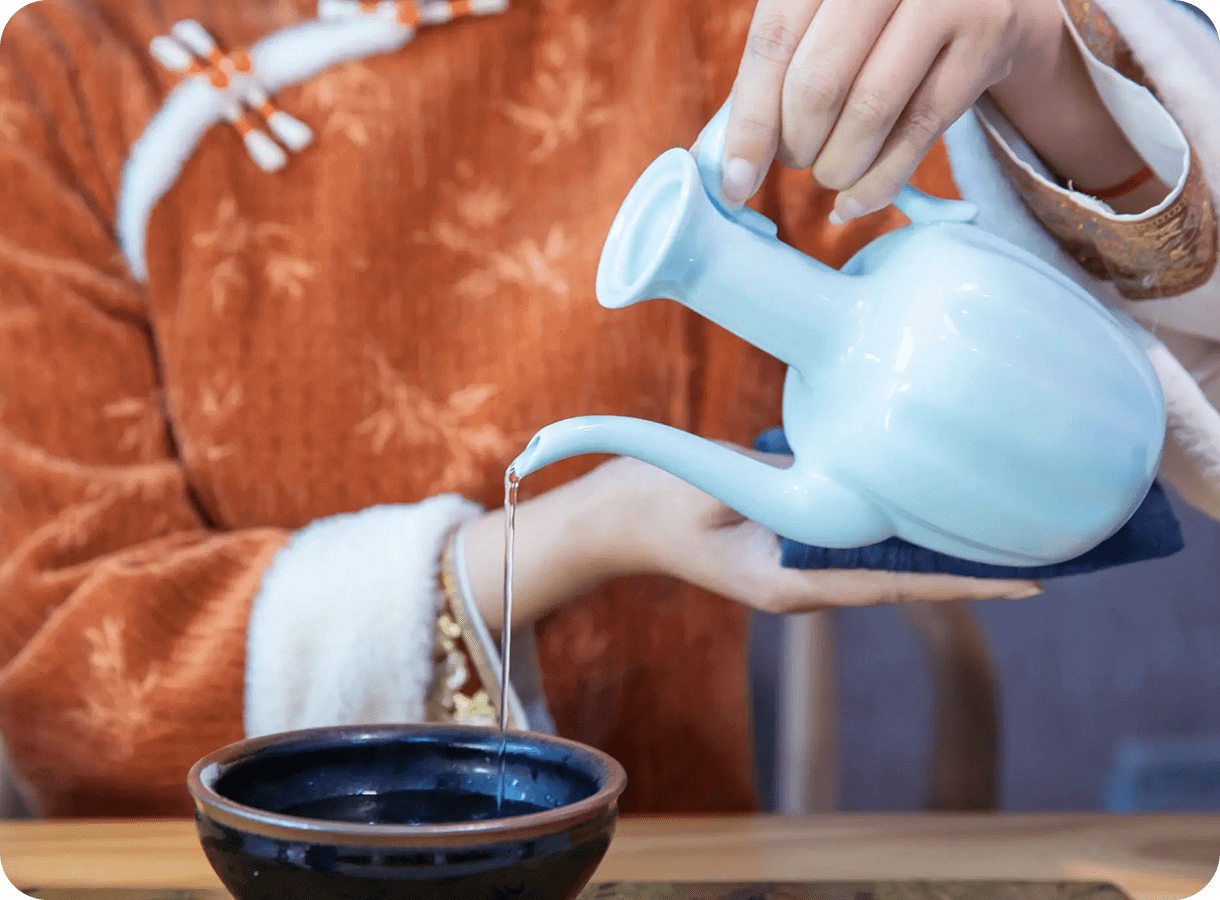 Pouring tea from white teapot into bowl.