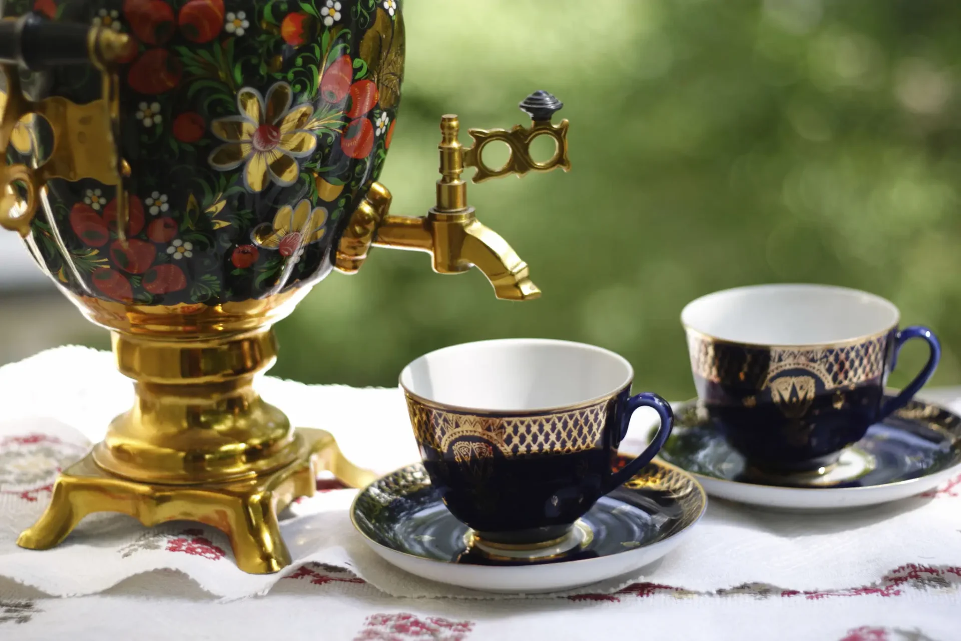 Elegant tea setup with a floral samovar and fine china cups.
