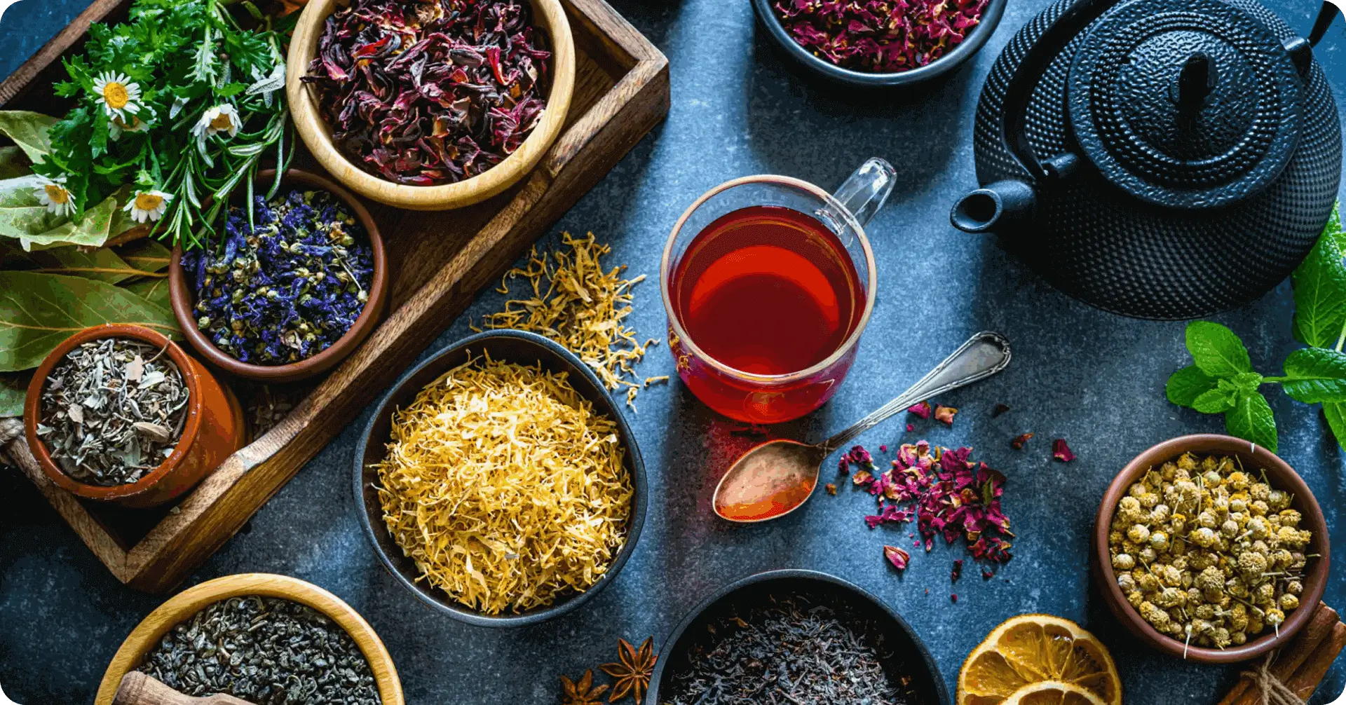 Glass cup of red herbal tea beside teapot